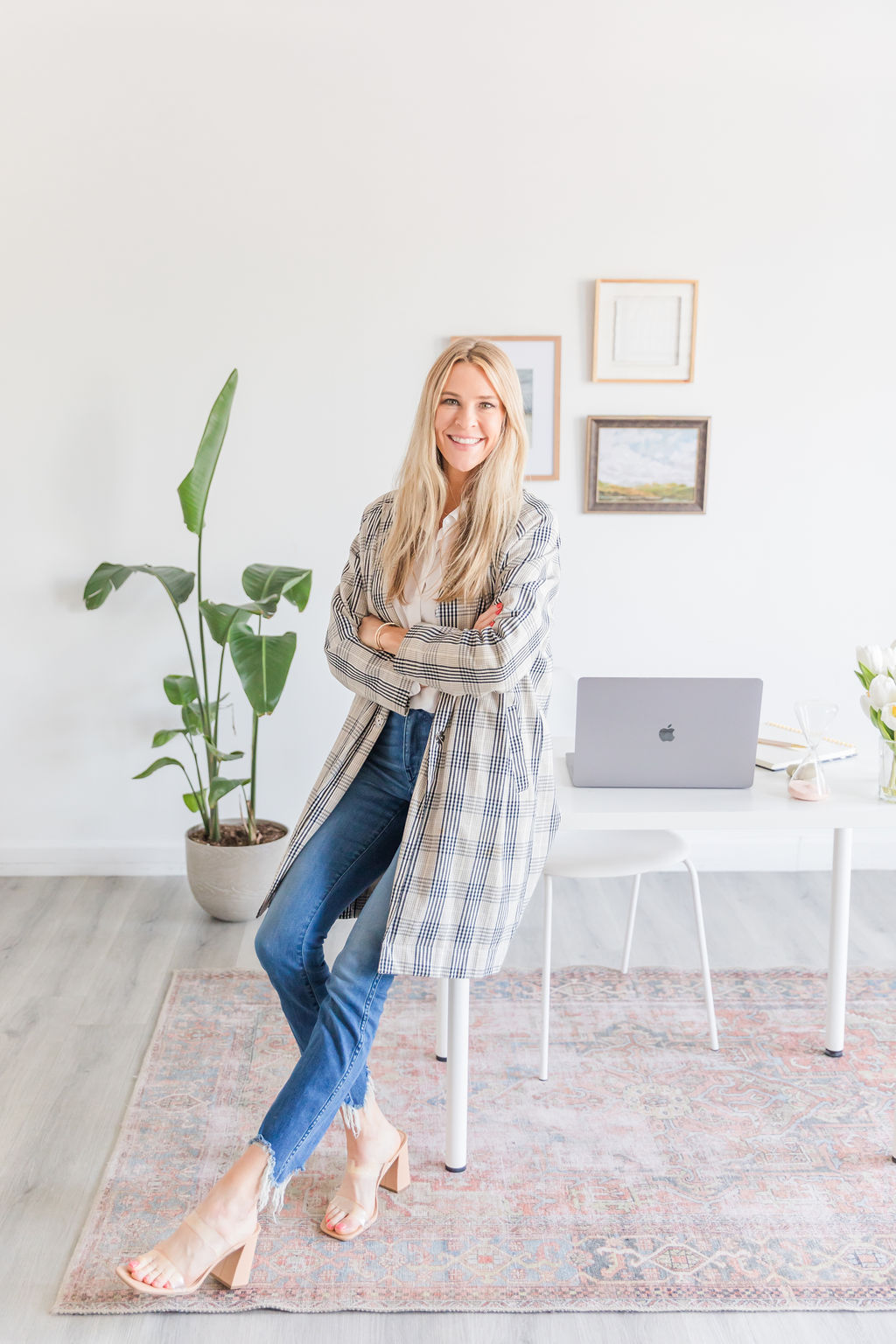 Chelsea Cadwell, owner and chief recruiter at Intoto Recruiting in Sioux Falls South Dakota standing in front of a desk and plant in a white office