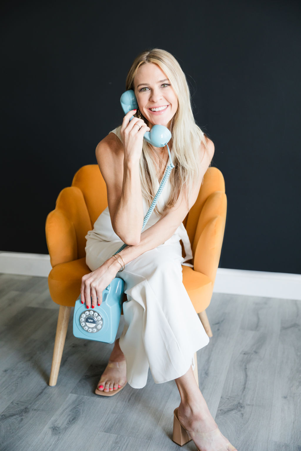 Chelsea Cadwell of Intoto Recruiting on the phone in a yellow chair in front of a black wall